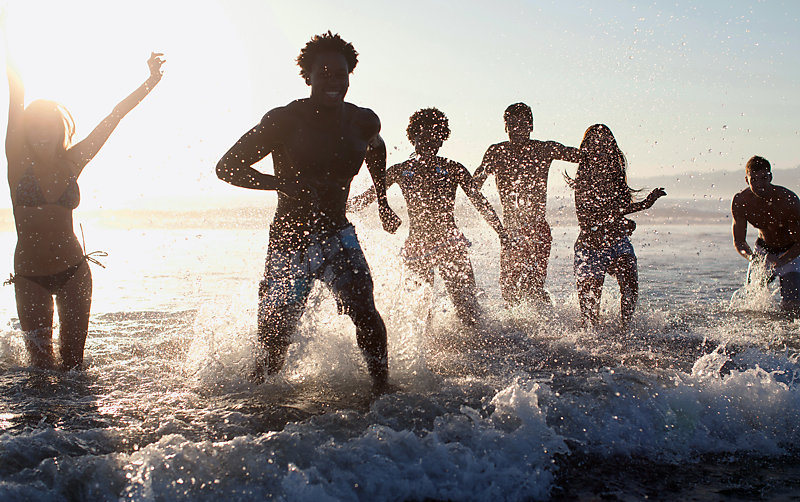 Friends on a beach, playing in waves.