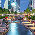 People elaxing by Cheong-Gyecheon stream in the centre of Seoul on a summer evening