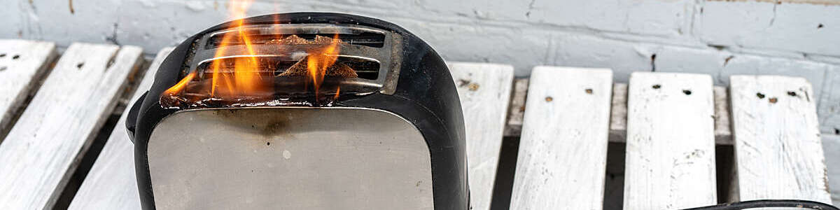 Burning toaster. Toaster with two slices of toast caught on fire over white background. Danger of careless handling of electrical appliances. Fire