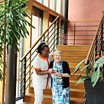 An elderly caretaker and an old woman smiling. 